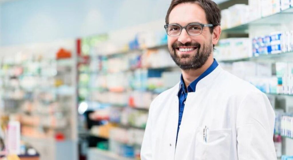 mercado farmacêutico: homem de jaleco branco em frente à prateleiras de medicamentos